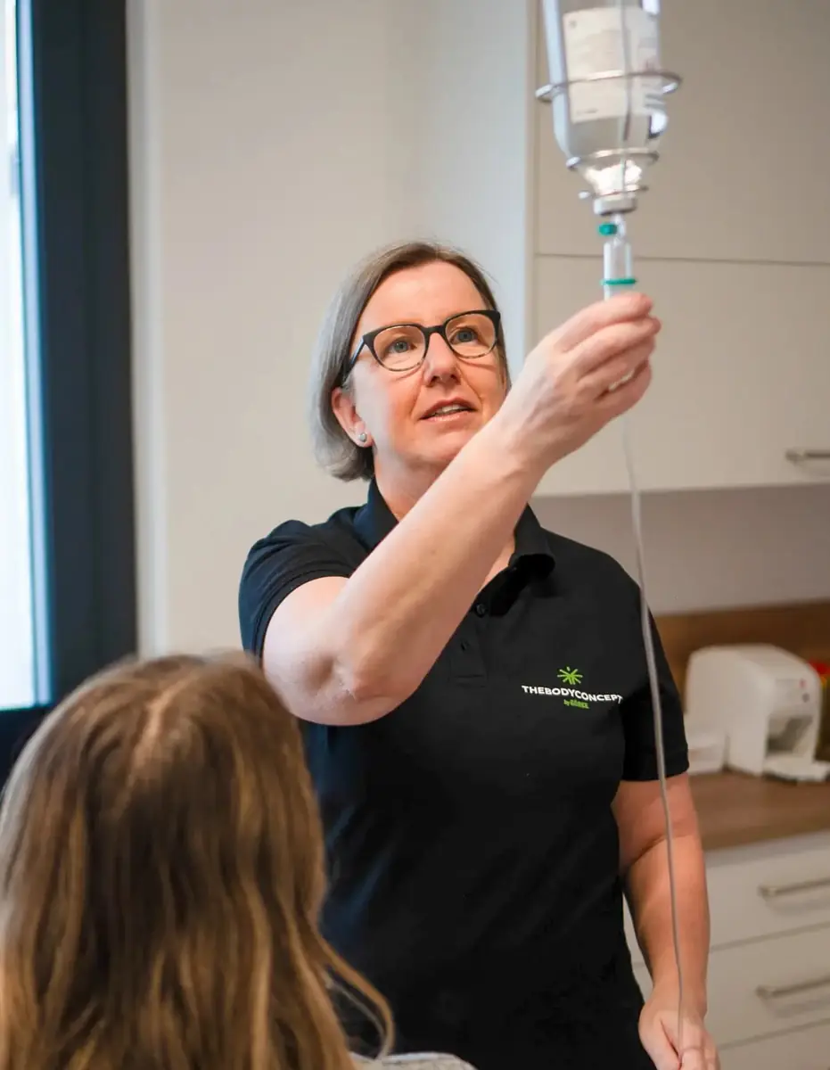 Mitarbeiterin bereitet im Behandlungsraum eine Infusion vor